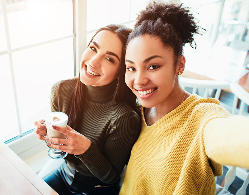 two young women taking selfie at coffee shop
